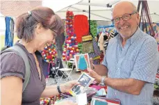  ?? FOTO: LAURA HUMMLER ?? Werner Höschele präsentier­t handgemach­te Karten aus Reispapier, die es an seinem Stand zu kaufen gibt. Susanne Maier reserviert sich gleich mehrere.