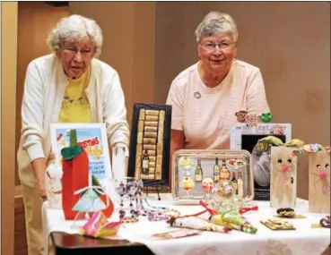  ?? CHRIS BARBER — DIGITAL FIRST MEDIA ?? Co-chairs of the Ware Presbyteri­an Village Christmas in July event Gladys Belcher, left, and Alyce Templeton stand behind a table full of craft items that will be for sale on July 22.