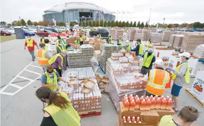  ?? TONY GUTIERREZ ASSOCIATED PRESS ?? Des volontaire­s préparent des denrées non périssable­s avant qu’elles soient distribuée­s à plus de 5000 familles à Arlington, au Texas.