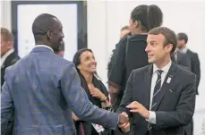  ?? EFE ?? El presidente francés, Emmanuel Macron (der.), estrecha la mano del atleta de EEUU ya retirado, Michael Johnson.