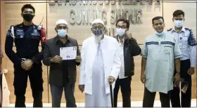  ?? CORRECTION­AL FACILITIES DIRECTORAT­E GENERAL VIA AP PHOTO ?? Islamic cleric Abu Bakar Bashir, center left, poses for a photo with lawyers, prison staff and his son Abdul Rohim, second right, before leaving Gunung Sindur prison upon his release, in Bogor, West Java, Indonesia, on Friday.