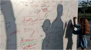  ??  ?? A girl signs on a white board to break the Guinness World Record in Abu Dhabi.