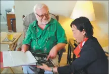  ?? RENA LI / CHINA DAILY ?? Lee Gardner (left) shows photograph­s of his family in Kuliang to Guo Ningning, vice-governor of Fujian province, on Sunday in El Segundo, California, in the United States.