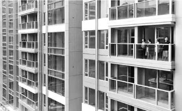  ??  ?? Visitors look from a balcony at a new flat in Park Yoho Genova, developed by Sun Hung Kai, in Hong Kong, China. With traditiona­l financing drying up in Hong Kong at a time when property prices are at a record high, home buyers like Fu are looking to...