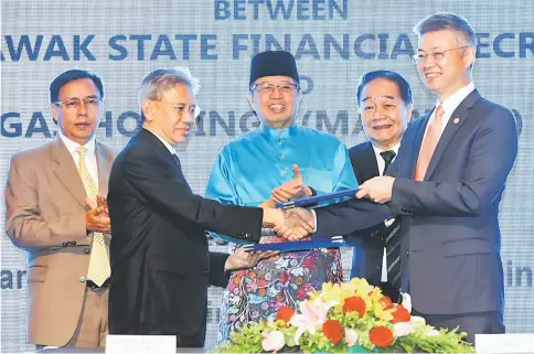  ??  ?? Abang Johari (centre), flanked by Wong (second right) and Dr Rundi (left), witnessing Lo (right) and Ahmad Tarmizi exchange the signed acquisitio­n documents. — Photo by Chimon Upon