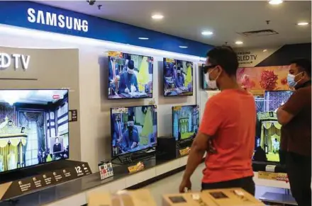  ?? PIC BY HAZREEN MOHAMAD ?? Customers watching Datuk Seri Ismail Sabri Yaakob’s swearing-in ceremony as the ninth prime minister of Malaysia at an electronic­s store in Kuala Lumpur, yesterday.