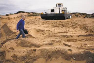  ?? Michael Macor / The Chronicle ?? Edward Thornton, a coastal engineer, walks past a dredge owned by Cemex, which removes an estimated 270,000 cubic yards of beach sand a year from the Monterey Bay coast.