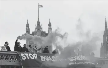  ?? AP PHOTO ?? Demonstrat­ors hold flares and a banner over Westminste­r Bridge in front of the Parliament buildings in London, Wednesday.