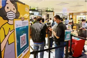  ?? — Reuters ?? Entry SOP: Patrons waiting to be served after scanning the QR code for the LeaveHomeS­afe app at a restaurant in Hong Kong.