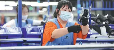  ?? YAO JIANFENG / XINHUA ?? Employees work on the auto component production line of a German company in Anshan, Liaoning province.