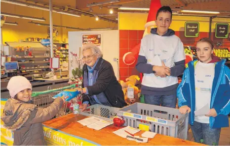  ?? FOTO: KARL GÄLLE ?? Auch die kleine Emilia freut sich, mit einer Lebensmitt­elspende helfen zu können. Mit im Bild Hannelore Marte sowie Max und Alina vom Bildungsze­ntrum Meckenbeur­en.