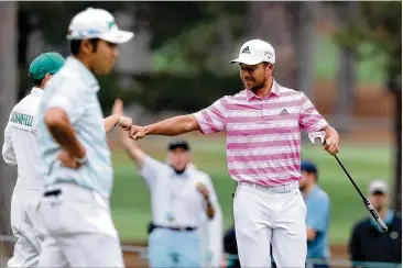  ?? PHOTOS BY CURTIS COMPTON/CURTIS.COMPTON@AJC.COM ?? Xander Schauffele fist-bumps his caddie after his eagle putt on the 15th hole Saturday; he and leader Hideki Matsuyama will be the final pairing for today’s final round.