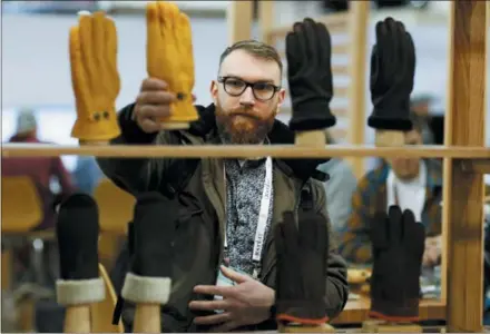  ?? DAVID ZALUBOWSKI — THE ASSOCIATED PRESS FILE ?? Theo Kerbourch looks over gloves for sale in the Hestia exhibit at the Outdoor Retailer &amp; Snow Show in the Colorado Convention Center in Denver. The National Retail Federation, the nation’s largest retail trade group, is forecastin­g that retail sales could grow between 3.8 percent and 4.4 percent to more than $3.8 trillion this year as shoppers remain in a mood to spend in a strong economy.