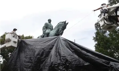  ?? Photograph: Steve Helber/AP ?? City workers drape a tarp over the statue of Robert E Lee in Charlottes­ville, Virginia, on 23 August 2017.