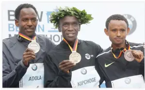  ??  ?? Winner Eliud Kipchoge of Kenya, center, second placed Ethiopian Guye Adola, left, and third placed Ethiopian Mosinet Geremew celebrate on the podium after the Berlin Marathon on Sunday in Berlin. (AFP)