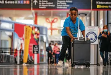  ?? Mark Mulligan / Staff photograph­er ?? Achinyu Konfor, 8, carries a suitcase for his aunt, who was headed back to the U.K., Tuesday at Bush Interconti­nental.