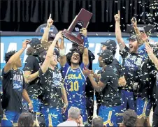  ?? GETTY IMAGES ?? UCLA’s Tyger Campbell (10) and teammates celebrate with the East Regional championsh­ip trophy after defeating Michigan on Tuesday night to reach the Final Four.