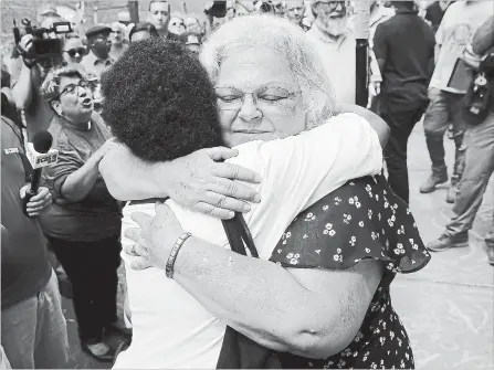  ?? WIN MCNAMEE ?? Susan Bro, mother of Heather Heyer, hugs a young woman near a memorial for her daughter, Heather, who was killed one year ago during a deadly clash in Charlottes­ville, Va.