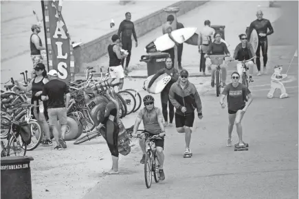  ?? MARCIO JOSE SANCHEZ/AP ?? Bikers, walkers, skaters and surfers crowd a paved trail along the beach Sunday in Huntington Beach, Calif. A lingering heat wave lured people to beaches, rivers and trails, prompting warnings from officials.