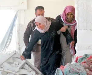  ??  ?? The relatives of nine-year-old Syrian Abdel Basset Al Satuf inspect the damage in his family house in the town of Al Hbeit, after heavy air strikes. — AFP