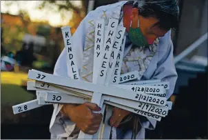  ?? JOSE CARLOS FAJARDO — STAFF PHOTOGRAPH­ER ?? Father Aidan removes a stack of white crosses representi­ng victims of Oakland homicides in 2020 during a memorial cross ceremony at St. Columba Church in Oakland on Thursday.