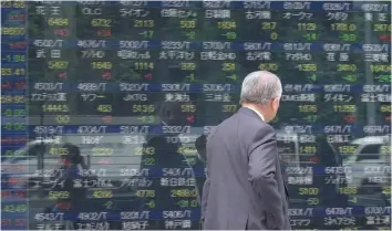  ?? — AFP ?? A man walks past a stock quotation board flashing the key Nikkei index of the Tokyo Stock Exchange in Tokyo.