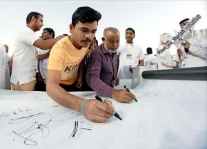  ?? Photos by M. Sajjad ?? Labourers giving their signatures to mark the Labour Day during the celebratio­ns organised by the Sharjah Labour Standards Developmen­t Authority at Al Sajaa Industrial area. —