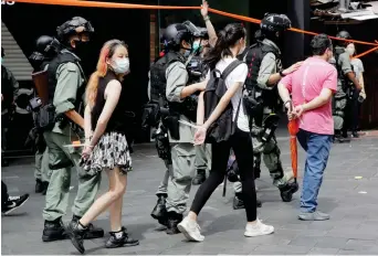  ?? Bild: Kin Cheung ?? Handfängsl­ade demonstran­ter förs bort av polis i Hongkong. Bilden togs i onsdags, dagen då den nya säkerhetsl­agen började användas.