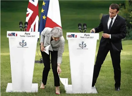  ?? Thibault Camus/Associated Press ?? Theresa May se atrapalha com papéis ao lado de Emmanuel Macron, durante pronunciam­ento conjunto em Paris