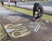  ?? JOE CAVARETTA/STAFF PHOTOGRAPH­ER ?? Lenar Nesmith of Pompano Beach, a fan of XXXTentaci­on, wrote a message on the sidewalk the day after the rapper was killed outside a Pompano motorcycle dealership.