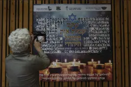  ?? PHOTOS BY TSAFRIR ABAYOV — THE ASSOCIATED PRESS ?? Above: A woman photograph­s a poster in memory of members of the Zionist youth movement undergroun­d in Hungary during the Holocaust at a ceremony awarding the Jewish Rescuers Citation at Kibbutz HaZorea, northern Israel, on Dec. 13. Right: Dezi Heffner-Reiner points to her photo on the poster.