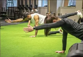  ?? Alexandra Wimley/Post-Gazette ?? Gym members Semerjit Bains and Alex Barr work out Wednesday at AltusHPO gym in Downtown. The class was limited to seven to enable participan­ts to stay about 6 feet apart.