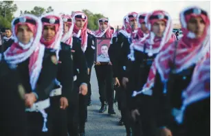  ?? (Muhammad Hamed/Reuters) ?? A JORDANIAN HONOR guard carries a picture of Lt.-Col. Saed Mayateh, who was killed on Sunday, at his funeral in Karak, Jordan, yesterday.