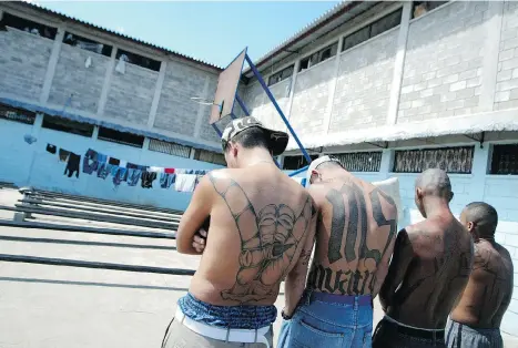  ?? ELMER MARTINEZ/AFP/GETTY IMAGES ?? Four tattooed members of the Mara Salvatruch­a MS-13 juvenile gang are imprisoned in the National Penitentia­ry in Tamara, Honduras. The gang’s American affiliates have allowed women to become members, and they are proving to be just as violent as men.