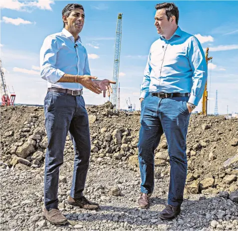  ?? ?? Rishi Sunak visits a building site at the Teesside freeport with Ben Houchen, the Mayor of Tees Valley. His choice of £500 Prada suede loafers for the trip caused some comment