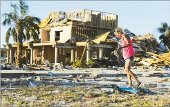  ??  ?? A resident looks for items to salvage from where her friend’s home once stood