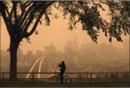  ?? The Canadian Press ?? A morning commuter stops to take a photo of the city as smoke from the B.C. wildfires rolls in over Edmonton on Wednesday.