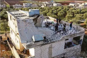  ?? Ghaith Alsayed / Associated Press ?? First responders inspect the top floor of a building damaged during a U.S. raid on a house in Atmeh, Syria. Thirteen people were reported killed, including six children and four women.