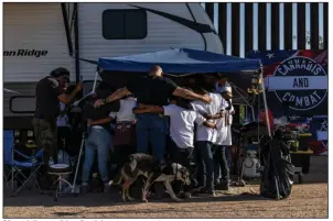  ?? (The New York Times/Adriana Zehbrauska­s) ?? QAnon followers Adam Bostick (left, in camouflage pants) and Justin Andersch (center, in black T-shirt) pray with migrant children from Guatemala at their group’s campsite on May 2, in Sasabe, Ariz.