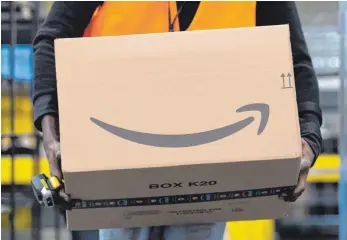  ?? FOTO: SEBASTIAN KAHNERT/DPA ?? Ein Sortiermit­arbeiter von Amazon trägt in einem Verteilzen­trum ein Paket: „Wenn Amazon hierher kommt, ist das ein verheerend­es Signal“, heißt es aus Teilen der Kommunalpo­litik.