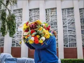  ?? ASSOCIATED PRESS ?? Benjamin Kisner of the Brookline neighborho­od in Pittsburgh removes flowers from the memorial for those killed during the October shooting at the Tree of Life synagogue, Wednesday, Nov. 14, 2018, in the Squirrel Hill neighborho­od of Pittsburgh.