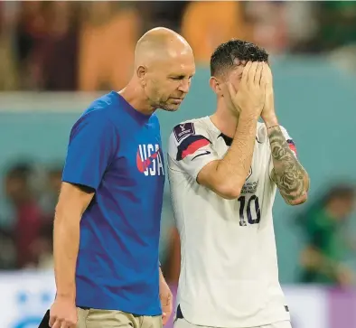  ?? MARTIN MEISSNER/AP ?? U.S. coach Gregg Berhalter walks with Christian Pulisic after losing in the knockout stafe of the World Cup on Saturday.