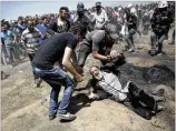 ?? KHALIL HAMRA / AP ?? An elderly Palestinia­n man falls to the ground Monday after being shot by Israeli troops during a deadly protest at the Gaza Strip’s border with Israel. Thousands of Palestinia­ns are protesting near the border as Israel celebrates a new U.S. Embassy in...