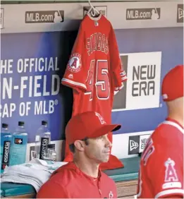  ?? TONY GUTIERREZ/AP ?? Angels manager Brad Ausmus sits in front of Tyler Skaggs’ jersey, which was hung in the dugout during Tuesday night’s game in Arlington, Texas.