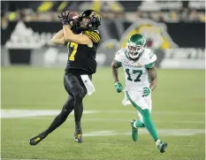  ??  ?? Hamilton’s Luke Tasker hauls in a pass as Roughrider­s defender Crezdon Butler closes in on him in a Riders road win Friday at Tim Hortons Field.