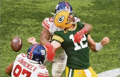  ?? Mike Hewitt / Getty Images ?? The Green Bay Packers’ Aaron Rodgers (12) is sacked by the New York Giants’ Oshane Ximines and fumbles the ball in the fourth quarter Sunday at Tottenham Hotspur Stadium in London.