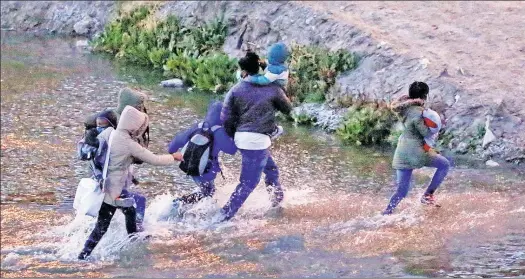  ??  ?? DESPERATIO­N: Asylum-seeking migrants traverse a shallow stretch of the Rio Bravo on Thursday before surrenderi­ng to Border Patrol guards in Texas.