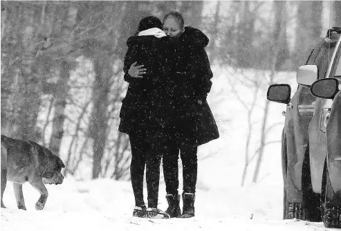  ?? DARREN MAKOWICHUK / POSTMEDIA NEWS ?? A family member is hugged as RCMP investigat­e a home in Morley, Alta., Wednesday where a small infant died and 13 children and an adult were taken to hospital in Calgary.