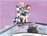  ?? Matt Sullivan / Getty Images ?? Kevin Harvick helps his son Keelan into the car with the checkered flag after winning Sunday.