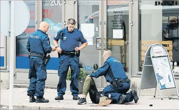  ?? KIRSI KANERVA / AFP ?? Tres policías atienden a una persona herida sobre la acera en el centro de la ciudad finlandesa de Turku